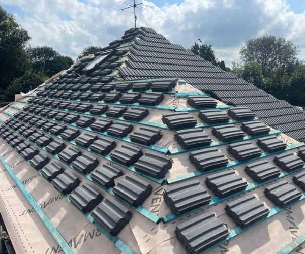 This is a photo of a new hip roof being installed. New felt, battens, and grey tiles have been installed, also a new velux window. Works carried out by HJT Roofing Gainsborough